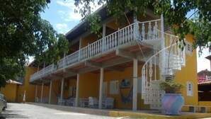 A two-story building with a balcony, a covered porch, and a large planter. - Pousada Recanto Rubaiyat (Ipojuca)