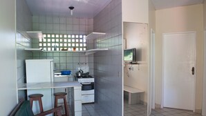 A compact kitchen with a refrigerator, stove, and a small dining area with stools. - Pousada Recanto Rubaiyat (Ipojuca)