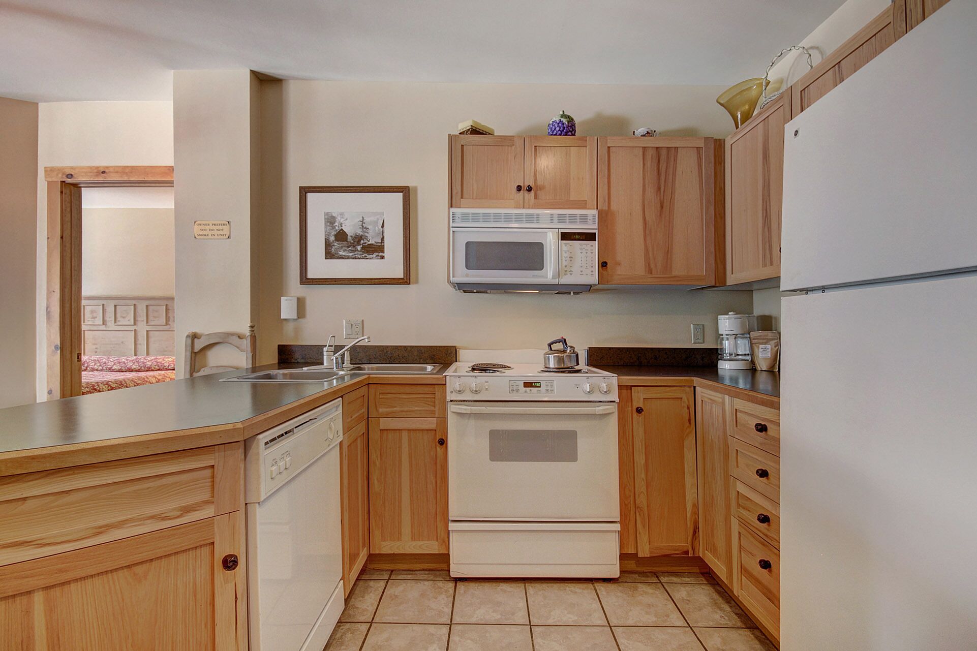 A compact kitchen with wooden cabinets, a microwave, a stove, and a dishwasher.