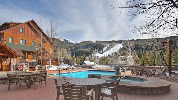 A pool area with outdoor seating and a view of snow-capped mountains. - 8493 Dakota Lodge (Keystone)