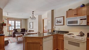 A kitchen with wooden cabinets, a built-in dishwasher, a stove, and a microwave. - 8493 Dakota Lodge (Keystone)