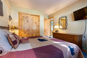 Ein Schlafzimmer mit einem großen Bett, einem Holzschrank, einer Kommode und einem an der Wand befestigten Fernseher.