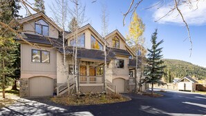 A two-story residential building with a covered front porch, a garage, and a driveway.