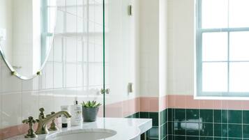 A bathroom with a white sink, a mirror, and a window.