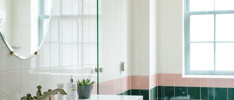 A bathroom with a white sink, a mirror, and a window.