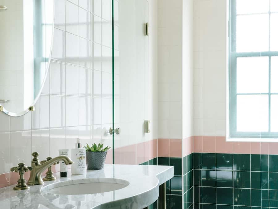 A bathroom with a white sink, a mirror, and a window.