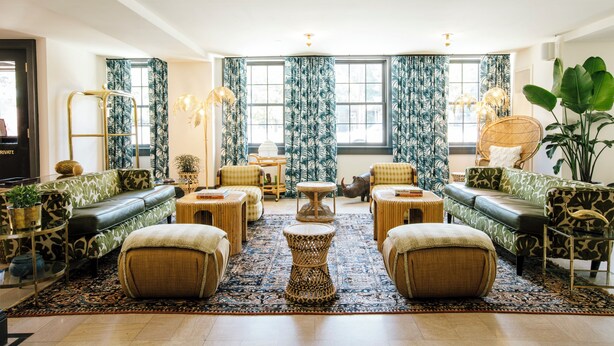 A spacious living room with a patterned sofa set, a central coffee table, and a large plant. - Hotel Clermont (Atlanta)
