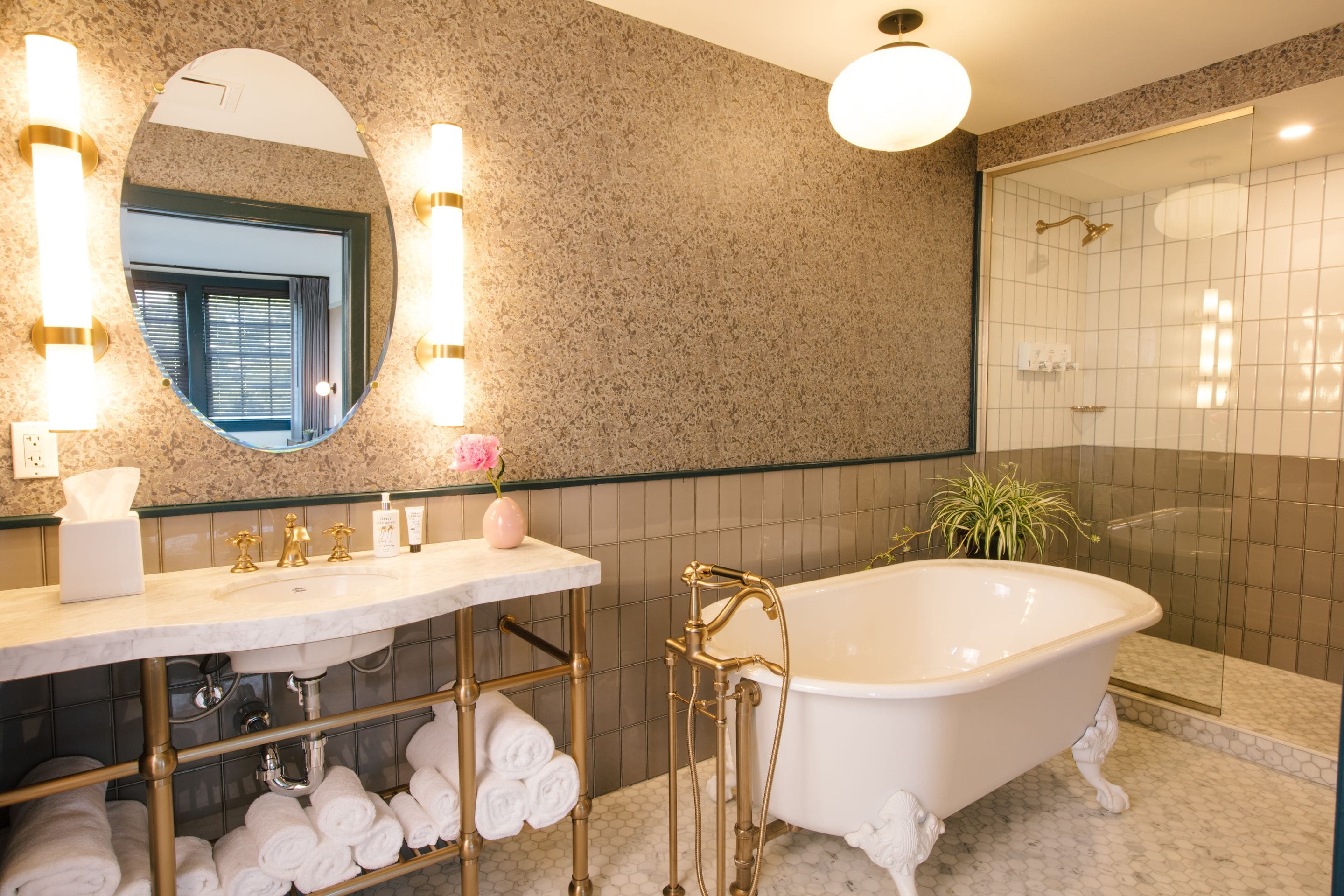 Een badkamer met een vrijstaand bad, een wastafel met spiegel en een douchehoek.