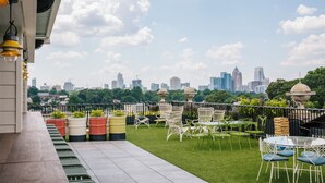 A rooftop terrace with a city skyline view, outdoor seating, and potted plants. - Hotel Clermont (Atlanta)