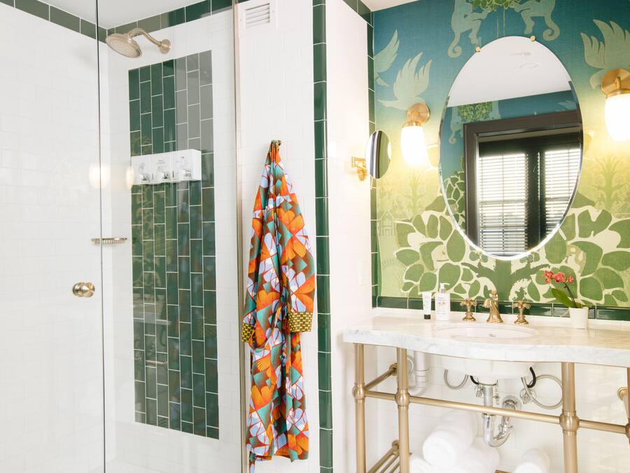 Een badkamer met een douche, een wastafel met spiegel, en een handdoek aan de muur.
