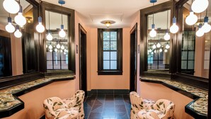 A hallway with mirrored walls, a central window, and seating areas with floral upholstery. - Hotel Clermont (Atlanta)