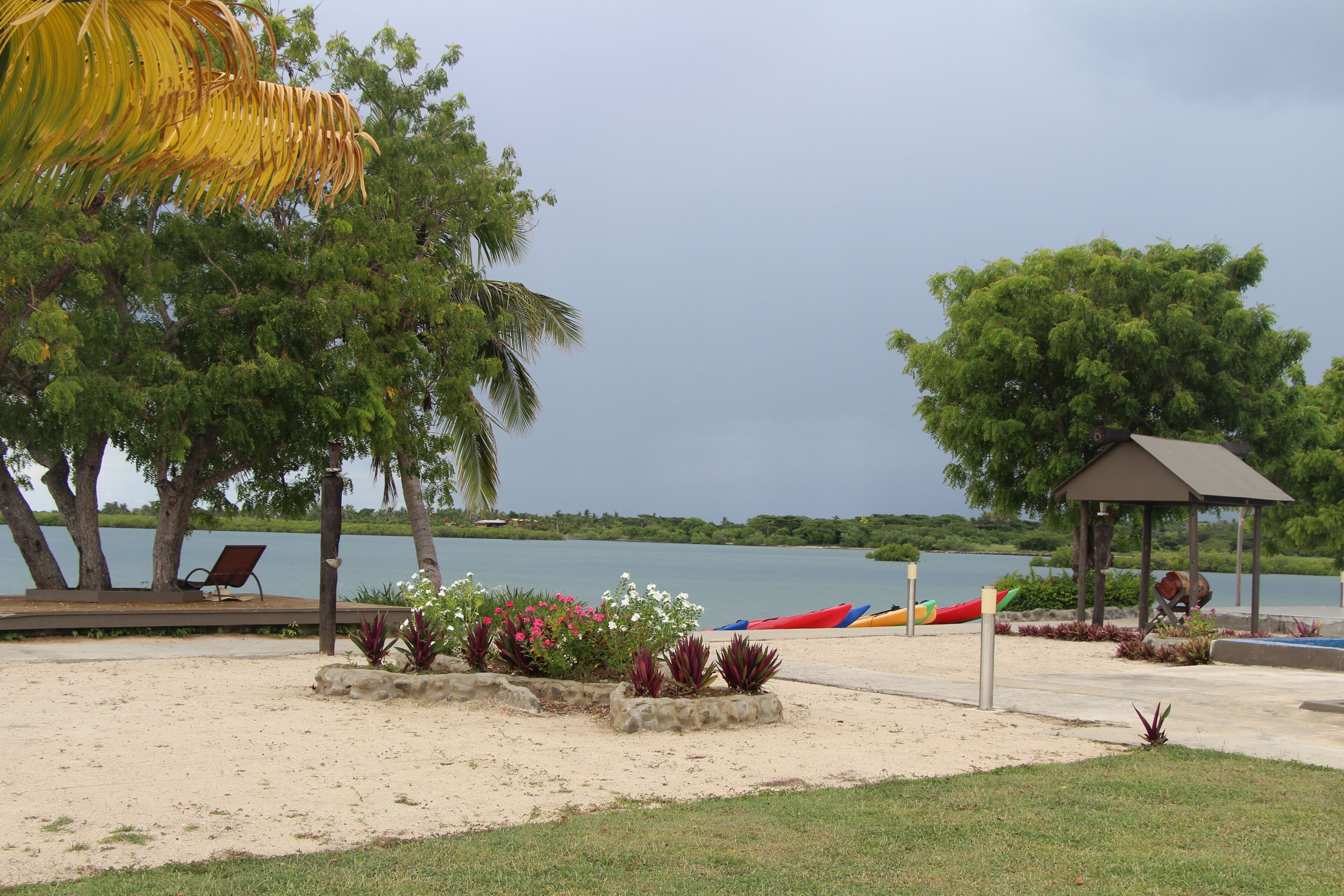 A lakeside park with a gazebo, benches, and kayaks.