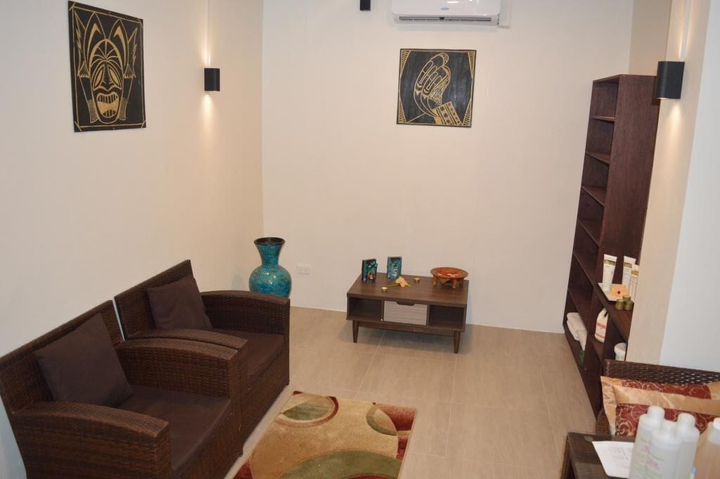 Ein Wohnzimmer mit einem braunen Rattan-Sofa, einer blauen Vase und einem kleinen Holztisch mit Dekoration.