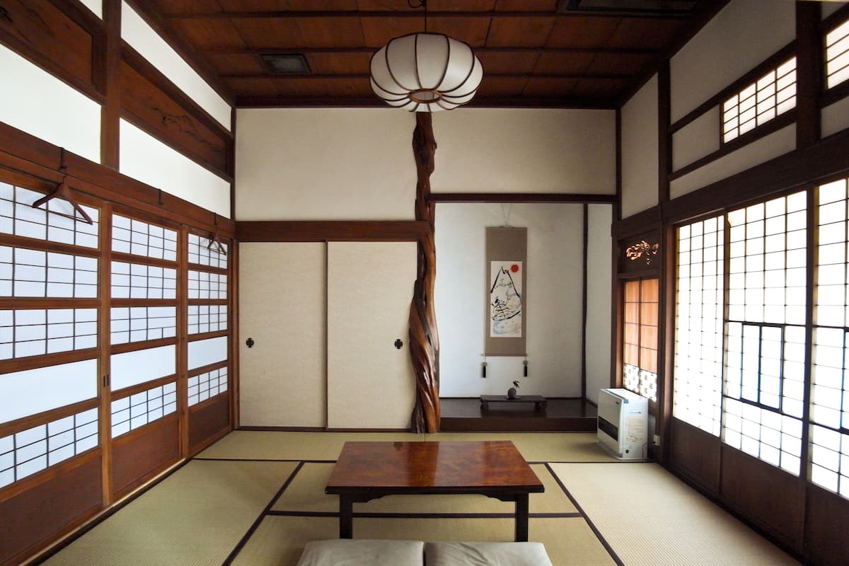 A traditional Japanese room with tatami flooring, a low wooden table, and sliding doors.