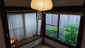 Una habitación con ventana, una lámpara colgante y una pequeña mesa con lámpara.