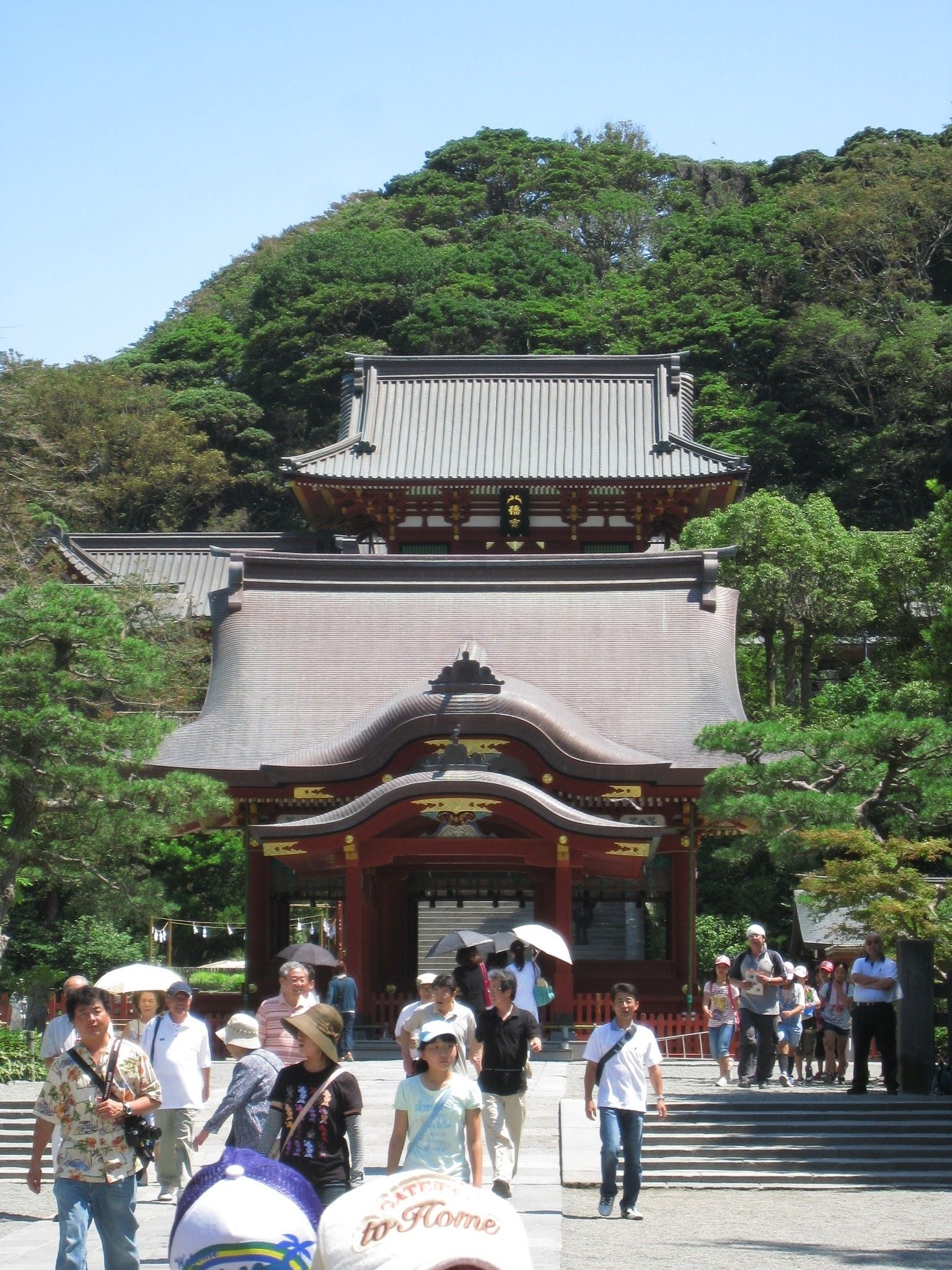 Un templo japonés tradicional con techo curvo y decoraciones ornamentales, rodeado de abundante vegetación.