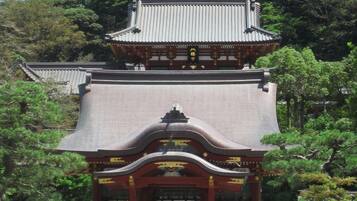 Un templo japonés tradicional con techo curvo y decoraciones ornamentales, rodeado de abundante vegetación.