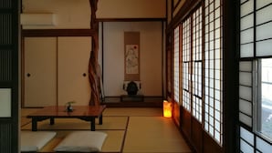 A traditional Japanese room with tatami flooring, a low table, cushions, a hanging lantern, and shoji screens. - Guest House Kamejikan (Kamakura)