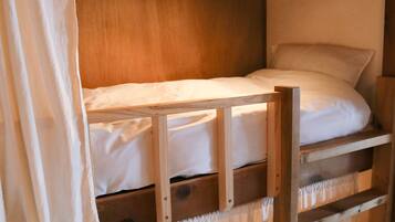 A bunk bed with a wooden frame and white bedding.