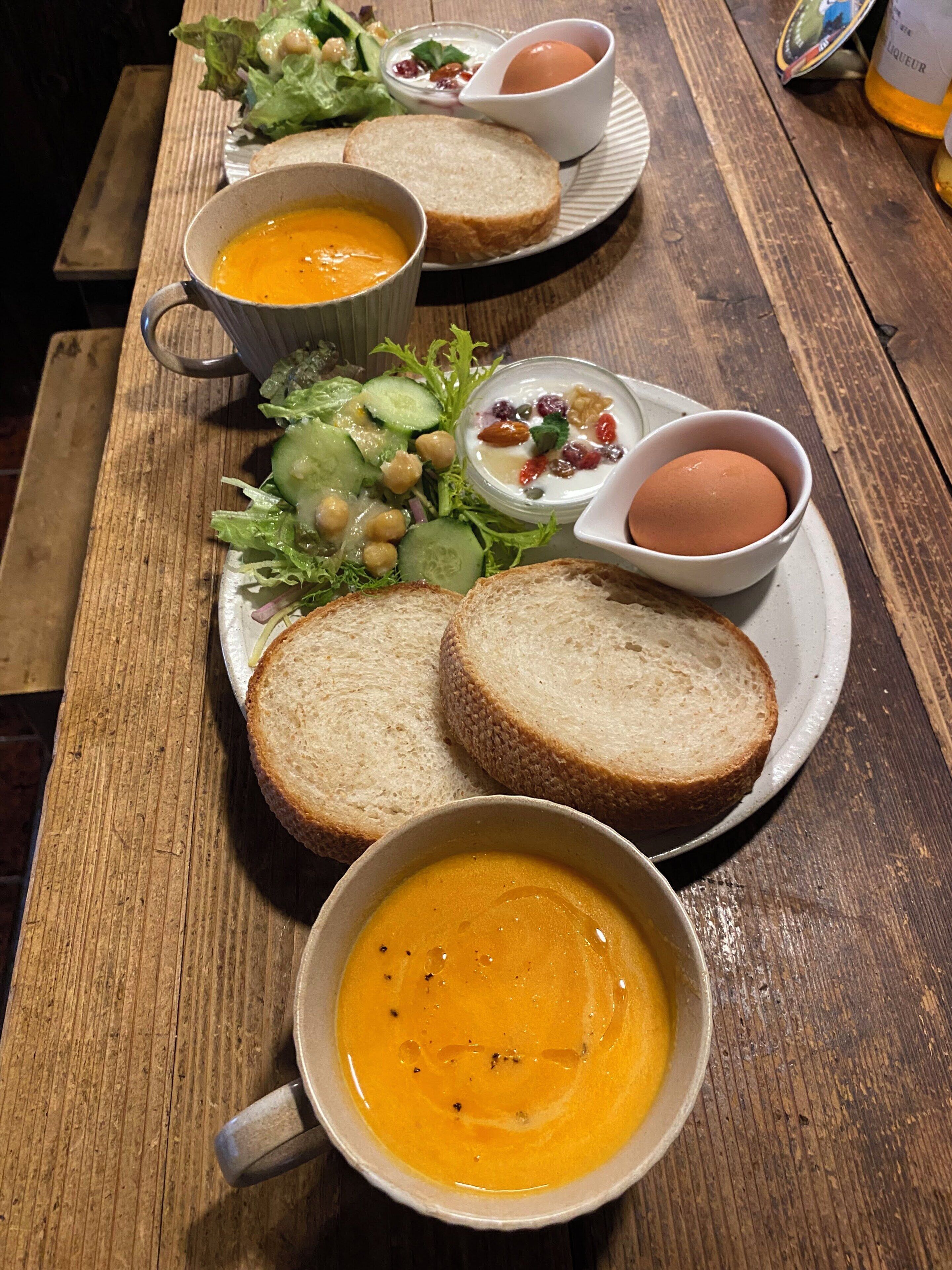 Puisesta pöydästä löytyy lautanen, jossa on ruokaa: leipää, keittoa, salaattia ja munia.