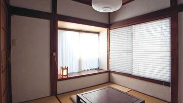A traditional Japanese room with tatami flooring, a low wooden table, a hanging paper lantern, and shoji screens.