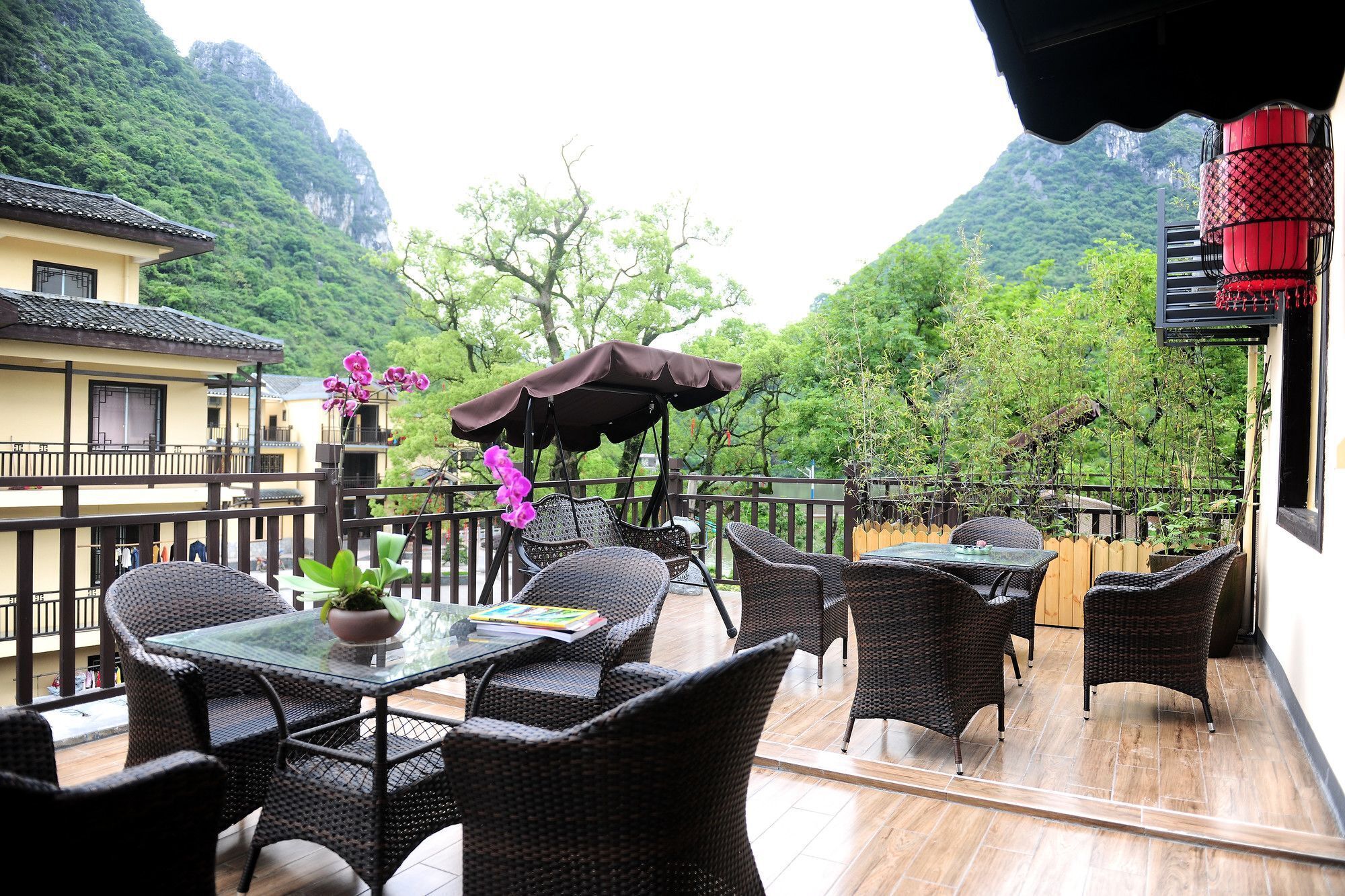 Un patio al aire libre con mobiliario de mimbre y una mesa de vidrio, con vistas a un paisaje montañoso.