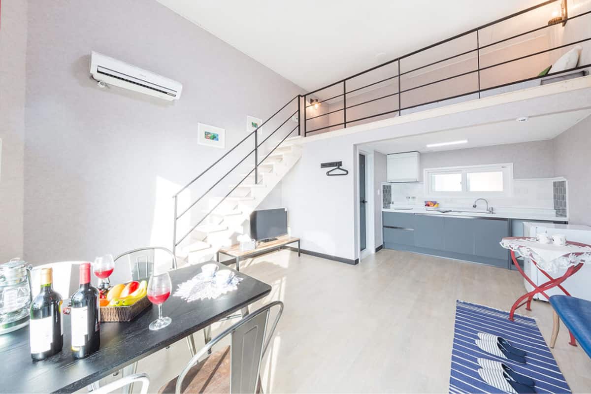Un appartamento moderno con zona pranzo, cucina e una scala che conduce a un livello superiore.