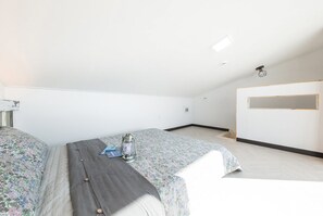 Un dormitorio con dos camas, una mesita y un estante en la pared.