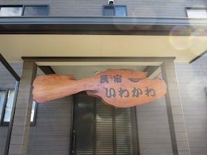 Entrada de un edificio con un letrero de madera que muestra caracteres japoneses.