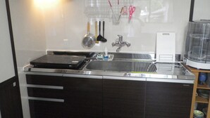 A modern kitchen with a stainless steel sink, a built-in stove, and a microwave. There are utensils hanging on the wall and a dish rack.