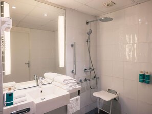 Een moderne badkamer met een wastafel, spiegel, handdoekhouder, douche en twee toiletartikelen.