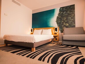 Een hotelkamer met een bed, een stoel, een wanddecoratie en een kamerbreed tapijt.