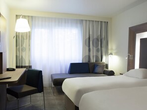 A hotel room with a bed, a desk, a chair, a sofa, and a window with curtains. - Novotel Le Havre Centre Gare (Le Havre)