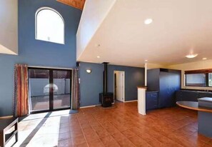 Un vaste espace de vie comprenant une grande porte-fenêtre coulissante, une cheminée et un coin cuisine.