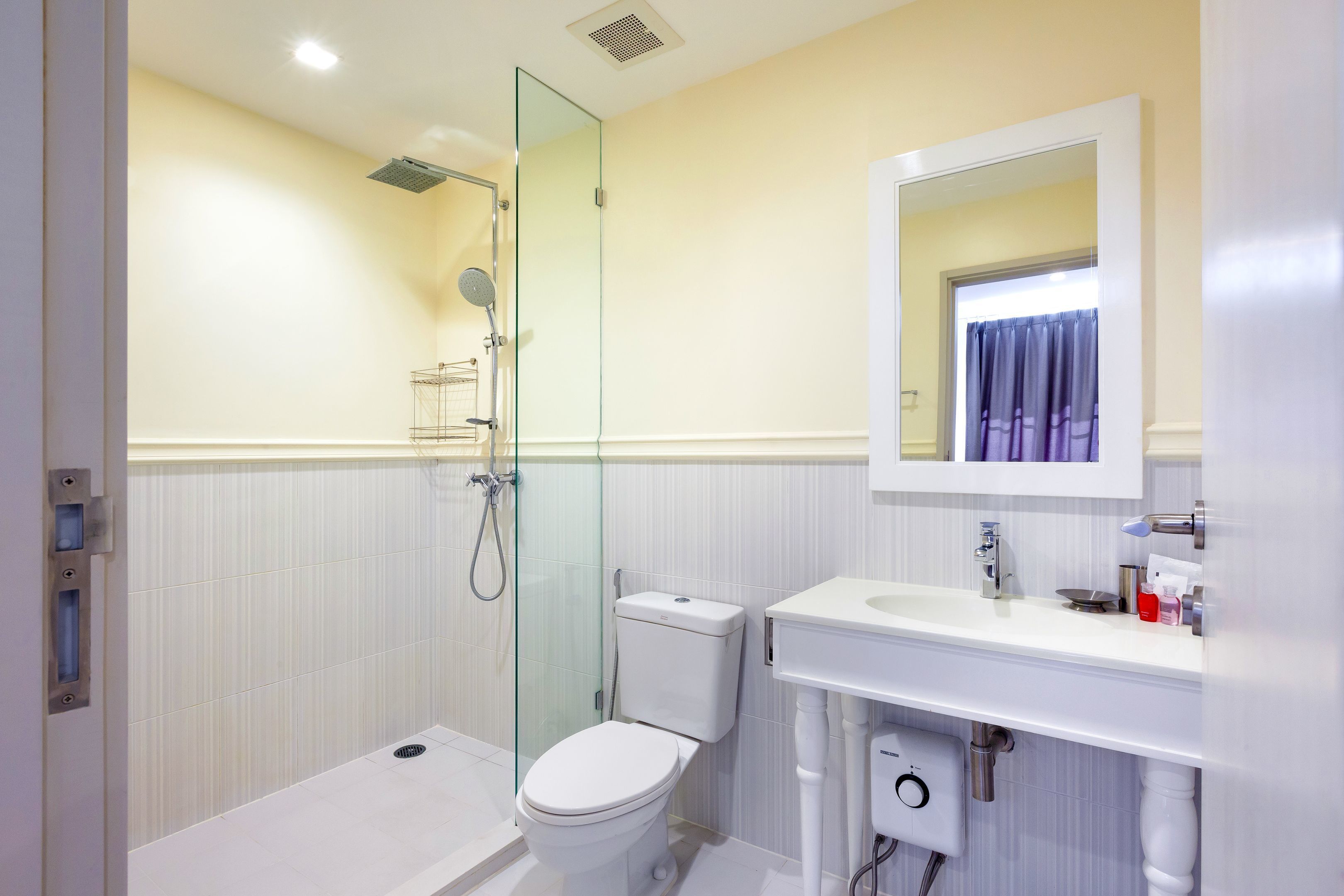 Une salle de bain moderne avec une douche à parois de verre, des toilettes blanches et un meuble-lavabo avec un miroir.