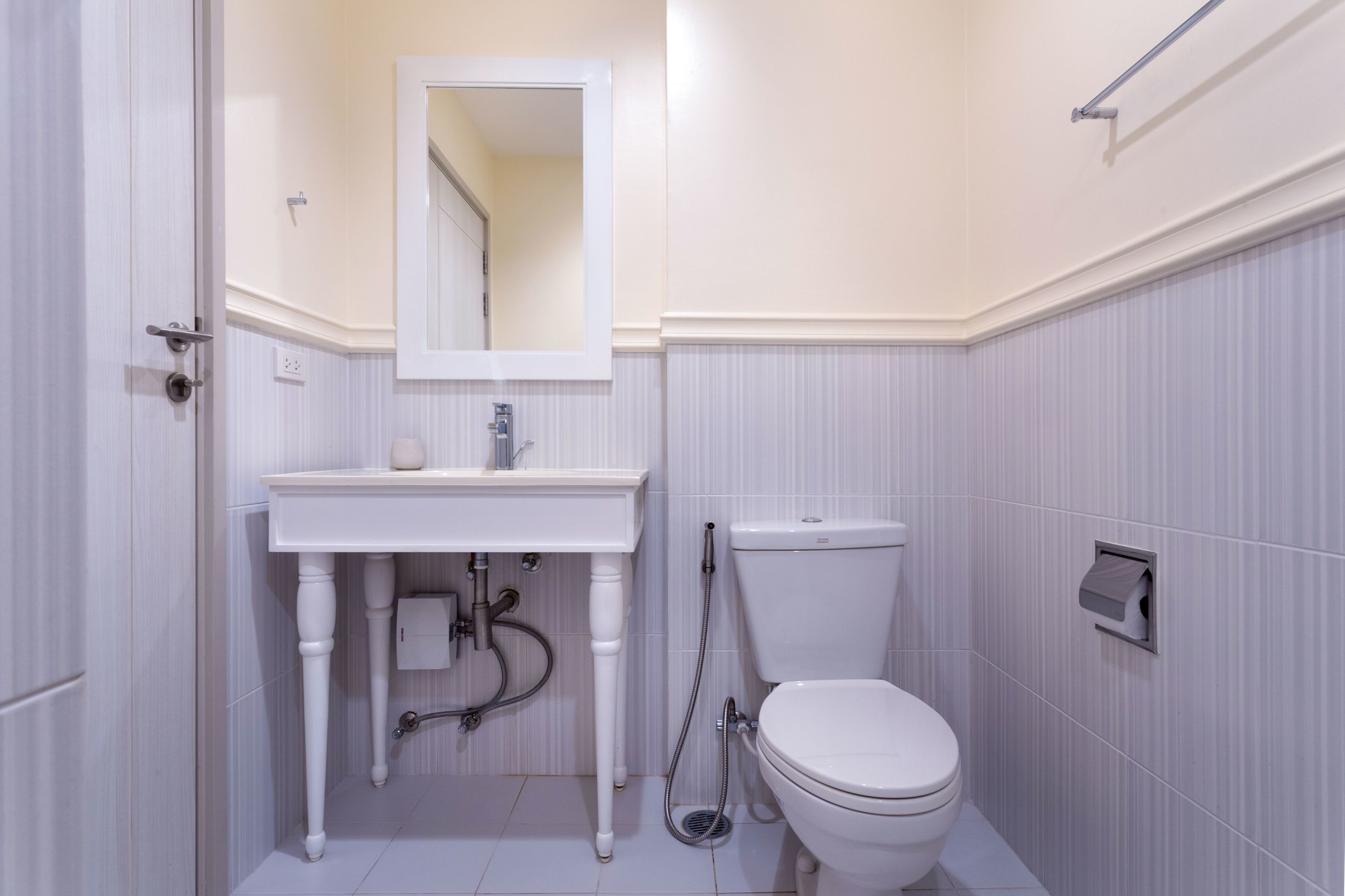 Une salle de bain avec un lavabo blanc, un miroir et des toilettes.