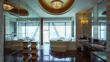 A luxurious bathroom with multiple sinks, a large bathtub, and a modern ceiling design.