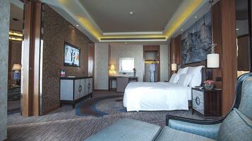 A hotel room with a large bed, a desk, a chair, and a TV.