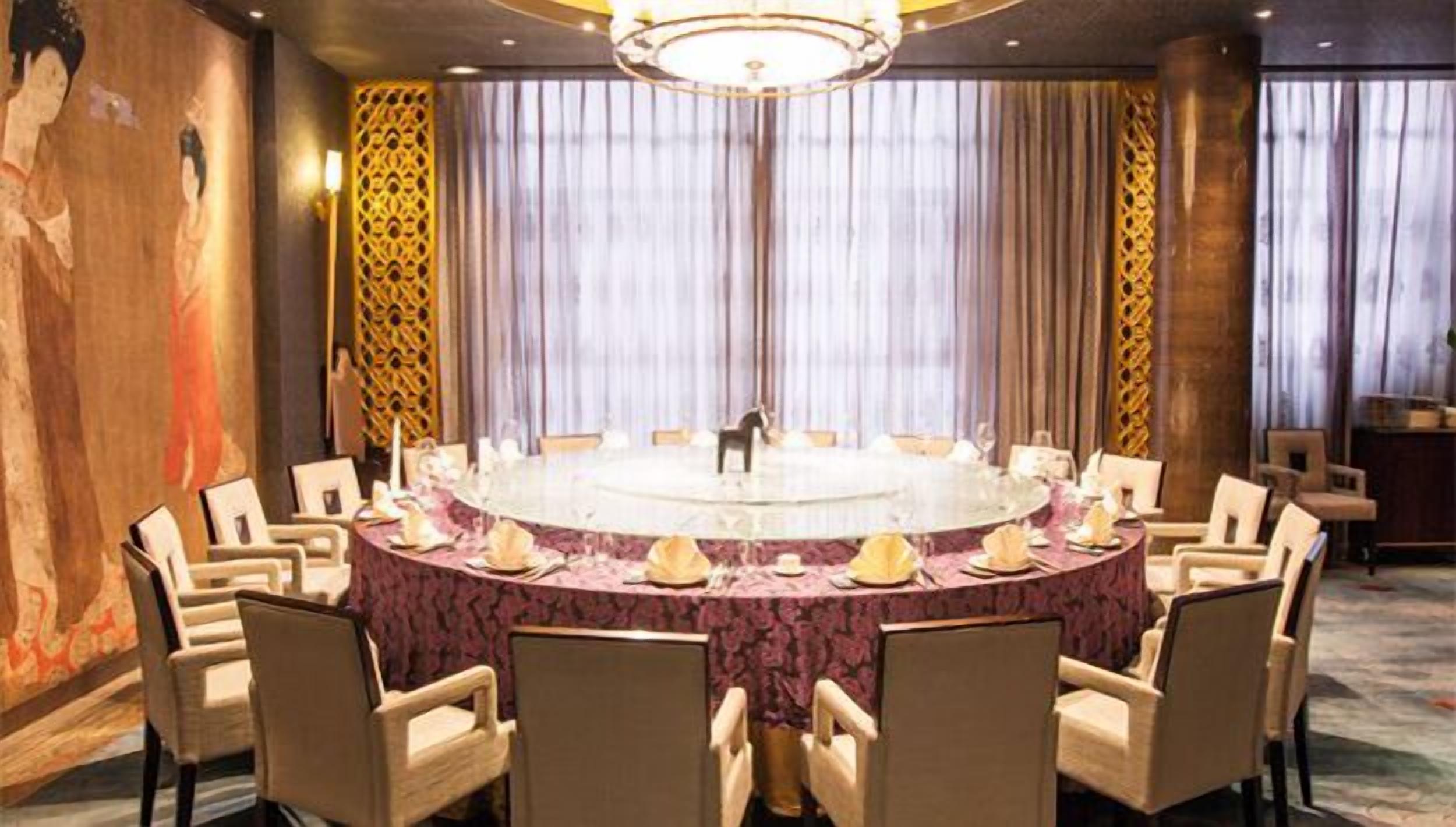 A conference room with a round table, chairs, and a chandelier.