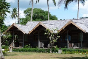A row of wooden cabins with pitched roofs, surrounded by lush greenery and palm trees. - New Ozone Resort & Spa (Ko Lanta)