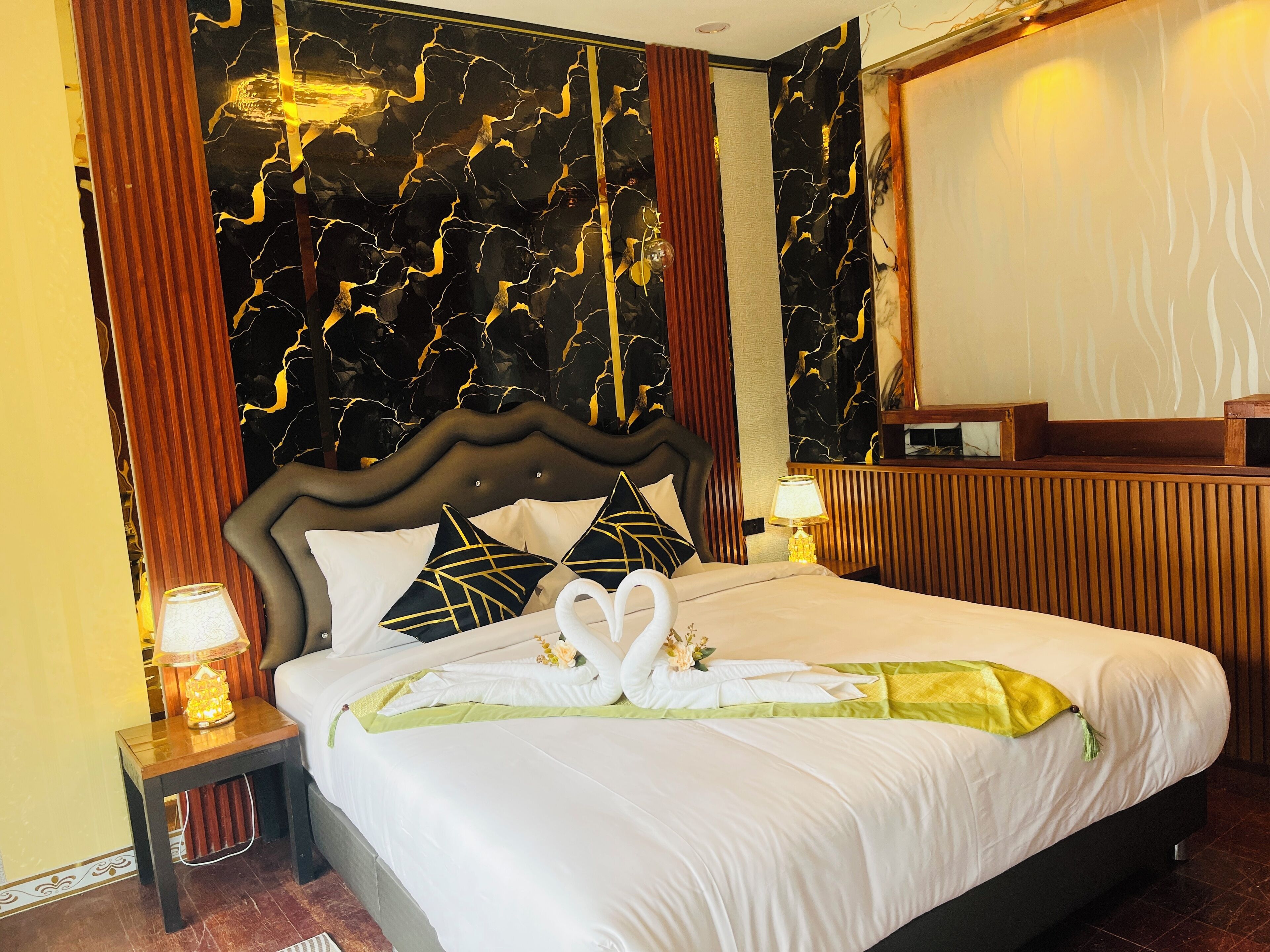 A hotel room with a large bed, a wooden headboard, and a marble-patterned wall.