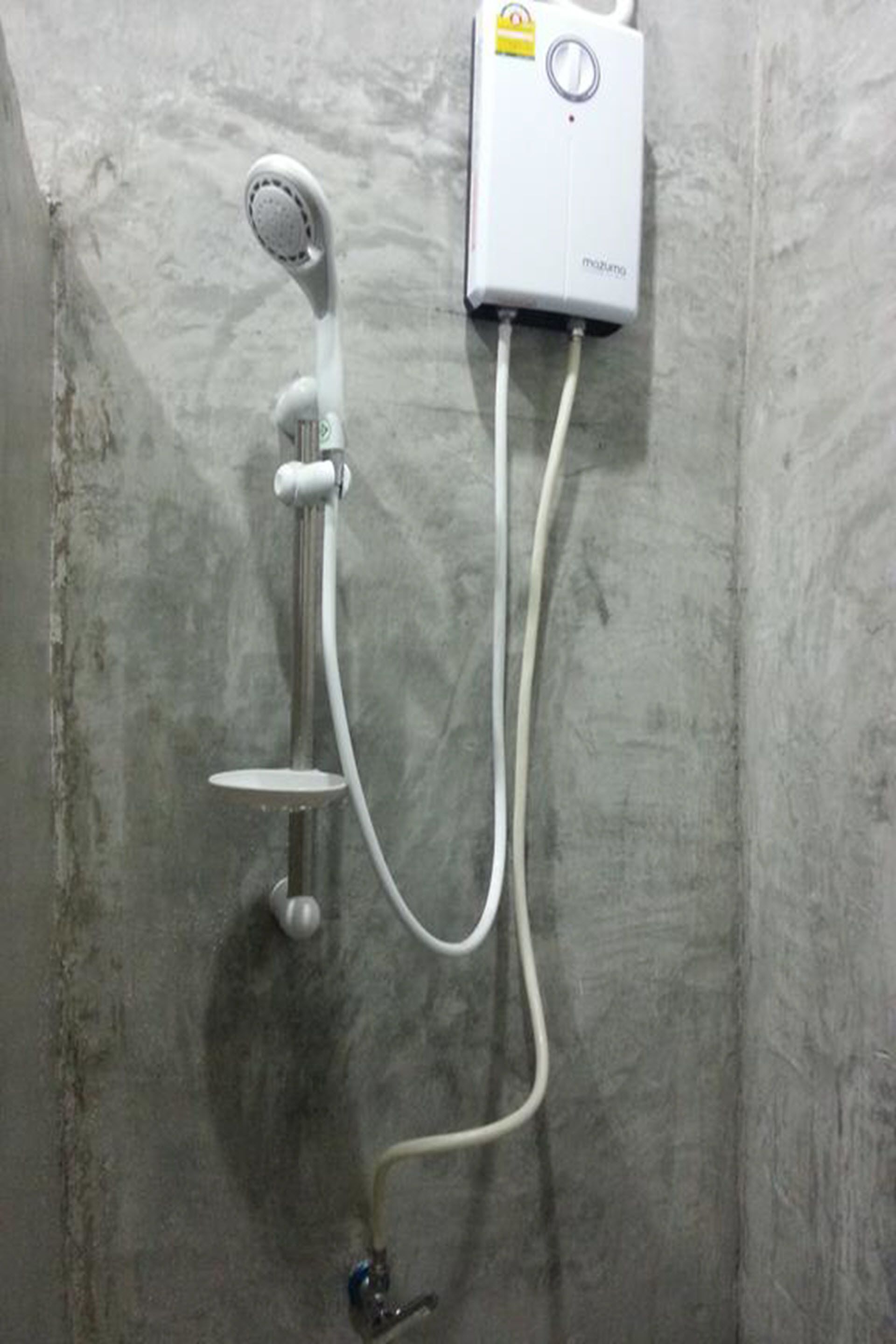 A bathroom with a wall-mounted shower unit, a handheld showerhead, and a control panel.