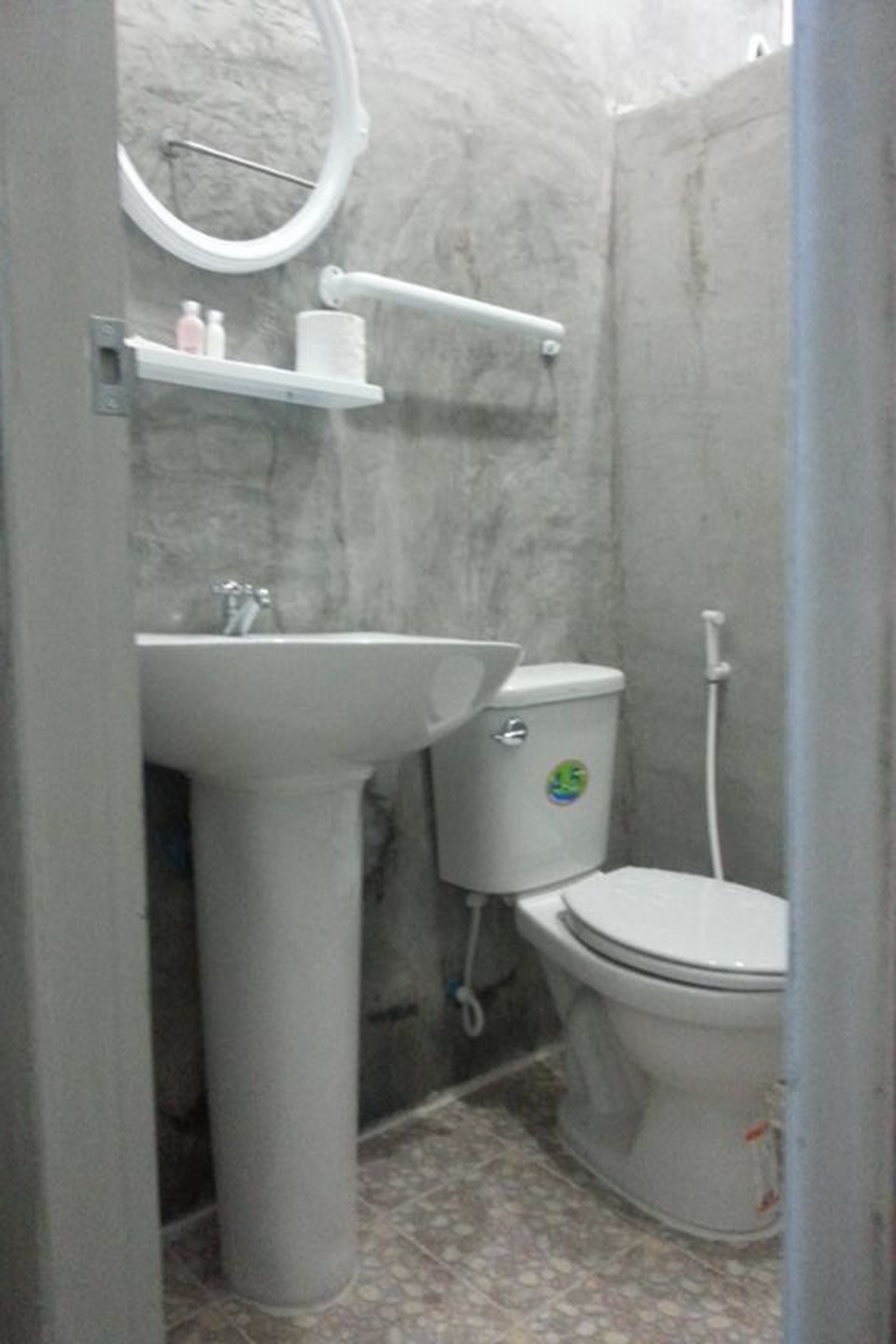 A bathroom with a pedestal sink, toilet, and a towel rack.