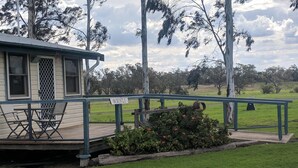A small building with a covered porch, a sign reading "Walnut," and a grassy area with trees in the background. - The Woolshed at Jondaryan - Campsite (Jondaryan)