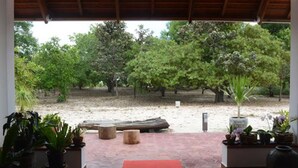 A covered outdoor area with a view of a garden and trees. - Dracaena Resort (Prasat Sambour)