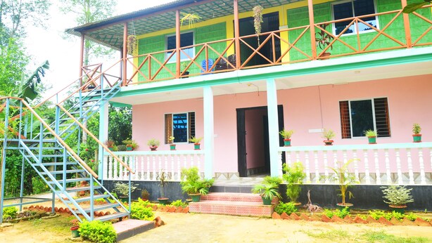 A two-story building with a balcony, a staircase, and potted plants. - Green Palace Tea Resort (Kamalganj)