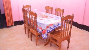 Une table à manger recouverte d’une nappe à motifs floraux, entourée de chaises en bois.