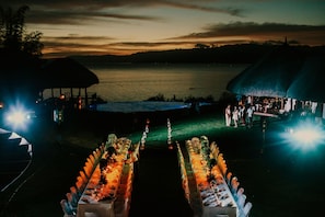 A lakeside dining setup with tables arranged in a semi-circle, overlooking the water. - Pure Shores Villa (Guindulman)