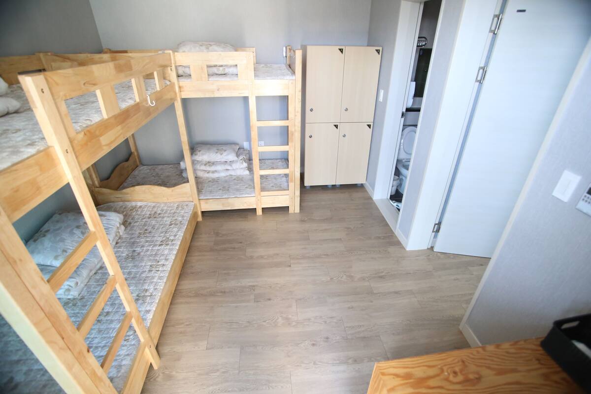 Una habitación con literas, un armario y una zona de cocina.