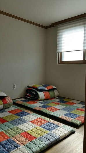 A small room with two beds, a window with blinds, and a power outlet on the wall. - Namu Guesthouse & Pension - Hostel (Yeosu)